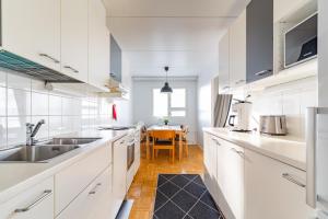 a white kitchen with a sink and a table at Kalastajankuja Apartment in Espoo