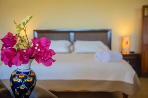 a vase with flowers on a table next to a bed at Beautiful Tropical House with Ocean VIEWS! in Cruz de Huanacaxtle