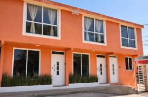 an orange house with white doors and windows at Hotel El Balcón in Zacatlán