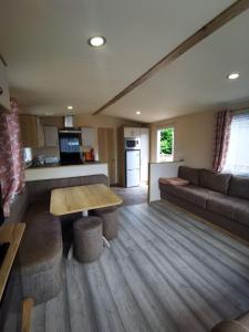 a living room with a couch and a table at Willows Lodge with self contained garden in Carlisle