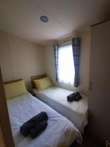 two beds in a small room with a window at Willows Lodge with self contained garden in Carlisle
