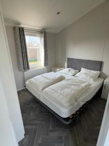 a bedroom with a large bed with white sheets and a window at Camping de Haas in Wolphaartsdijk