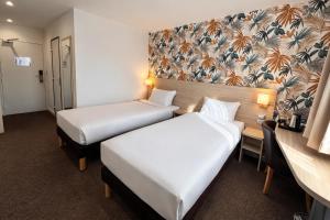 ein Hotelzimmer mit zwei Betten und einem Schreibtisch in der Unterkunft Logis Hotel Altina in Pacy-sur-Eure + 83 Fotos