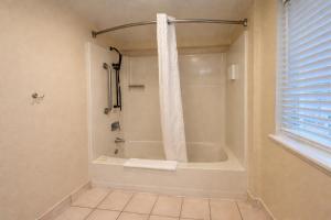 a bathroom with a tub and a shower with a window at Bay Breeze Inn in Seaside
