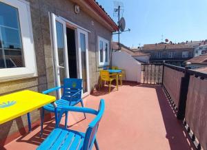 a balcony with tables and chairs and a yellow table at A Barca de Pedra in Padrón