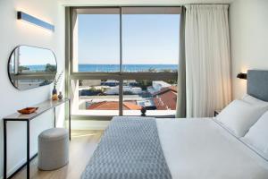 a bedroom with a bed and a large window at L Residences & Suites in Larnaca