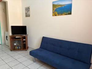 a blue couch in a living room with a tv at Escapade Océane in Quartier du Fond Fleuri