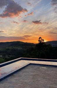 Ein Swimmingpool mit Sonnenuntergang im Hintergrund in der Unterkunft Carmelo Morada do Sol in Tomazina