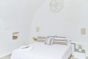 a white bedroom with a white bed with striped pillows at Masseria Mozzone in Fasano +78 photos