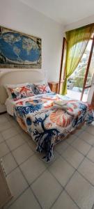 a bedroom with a bed with a colorful comforter and a window at Perla del Mare in Sperlonga
