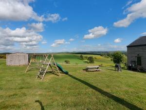 a playground with a slide and a bench in a field at Holiday Home A Pas de Loup in La-Roche-en-Ardenne
