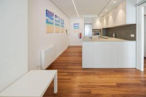 a kitchen with white cabinets and a wooden floor at Bañeru Zarautz Centro - Sol, playa y confort, todo a un paso in Zarautz +15 photos