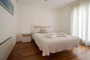 a white bedroom with a bed with two towels on it at Bañeru Zarautz Centro - Sol, playa y confort, todo a un paso in Zarautz