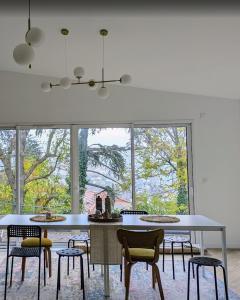 a dining room with a table and chairs and windows at Maison Terracotta in Saint-Priest-en-Jarez