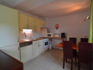 una cocina con armarios blancos y una mesa con sillas. en House adjoining mansion for a pleasant stay in the region of Chimay, en Plagneau