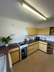 a kitchen with yellow cabinets and a stove top oven at Penrhyn View in Bangor