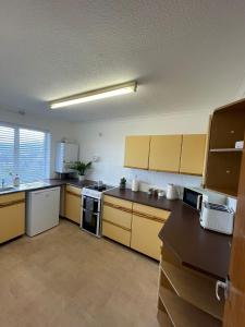 a large kitchen with yellow cabinets and appliances at Penrhyn View in Bangor