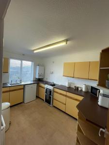 a large kitchen with yellow cabinets and appliances at Penrhyn View in Bangor +9 photos