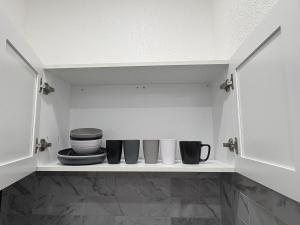 a shelf with bowls and cups on it in a kitchen at Miami Stay - Pool, Parking, & Affordable Transportation in Tamiami +27 photos
