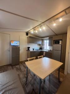 a kitchen with a wooden table and a table and chairs at Les mobil homes de NOLY TV CLIM 6places 1 place adulte offerte pour la réserve africaine sigean in Port-la-Nouvelle