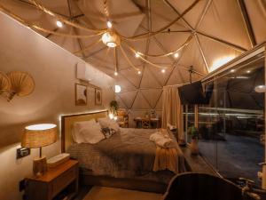 a bedroom with a large bed with a ceiling with lights at Goat Lodge DOMO BALI in Ibiúna