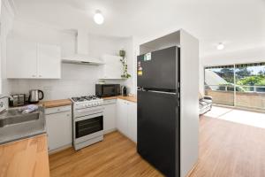 a kitchen with white cabinets and a black refrigerator at Georgies Simple Base in Mosman Park in Mosman Park
