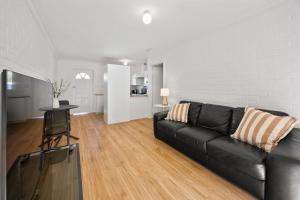 a living room with a black couch and a table at Georgies Simple Base in Mosman Park in Mosman Park