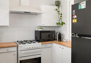 a white kitchen with a stove and a microwave at Georgies Simple Base in Mosman Park in Mosman Park +9 photos