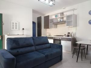a living room with a blue couch and a kitchen at Sole e relax da Michelle in Anzio