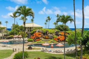 a resort with a pool and palm trees at Pristine Hotel Room at Popular Resort in Lihue