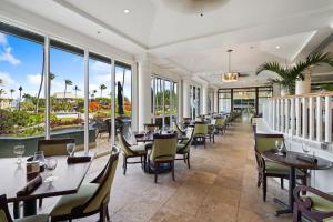 a restaurant with tables and chairs and large windows at Pristine Hotel Room at Popular Resort in Lihue