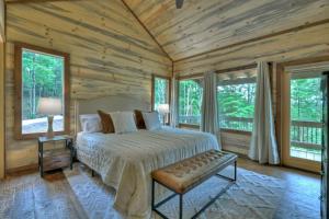 a bedroom with a bed in a room with wooden walls at Altitude Adjustment- Luxury 3BR Cabin w/ Outdoor Living Area & Hot Tub in Epworth