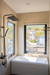 a bathroom with a large white tub and a window at ArionHotel in Ninh Hải