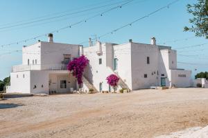 a large white building with purple flowers on it at Masseria Mozzone in Fasano