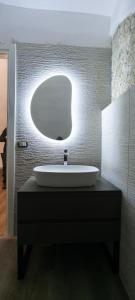 a bathroom with a sink and a round mirror at Guesthouse Acherusia in Bacoli +26 photos