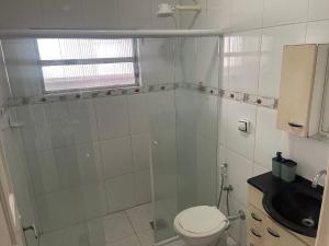 a white bathroom with a toilet and a sink at Apto no Canto do Forte com garagem in Praia Grande