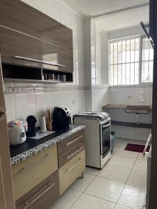 a kitchen with a stove and a microwave at Apto no Canto do Forte com garagem in Praia Grande