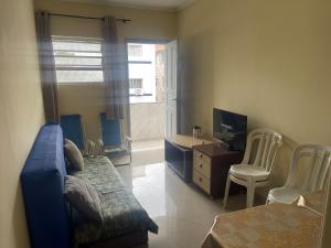 a living room with a couch and a desk and a television at Apto no Canto do Forte com garagem in Praia Grande
