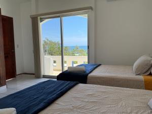 a bedroom with two beds and a large window at VISTAMAR Casa a pie de Playa in Playa Agua Blanca