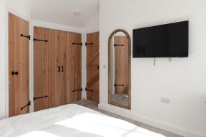 a bedroom with a mirror and a tv on a wall at Sunray Cottage in Weymouth