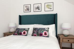 a bed with two pillows on it with three pictures on the wall at Sunray Cottage in Weymouth