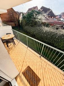 a wooden deck with a table and chairs on a balcony at Appartement cosy à 10 min de Strasbourg - Bischheim in Bischheim