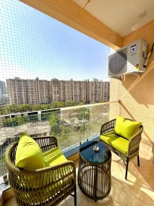 a balcony with two chairs and a table and a large window at Lux Lettings in Noida