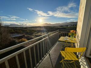 a table and a chair on a balcony with a view at Europe's last sunset in Waterville