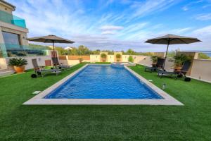 a swimming pool on a lawn with umbrellas at Masanda in Ždrelac +55 photos