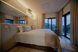 ein Schlafzimmer mit einem großen Bett und einem großen Fenster in der Unterkunft Hotel Cantuccio in Arroio Trinta