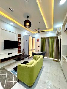 a living room with a green couch and a tv at Lux Lettings in Noida