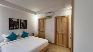 a bedroom with a white bed with blue pillows at Strandwohnung Taghazout mit Meerblick, Terrasse, Garten & Pool 2 Min zum Surfspot in Taghazout
