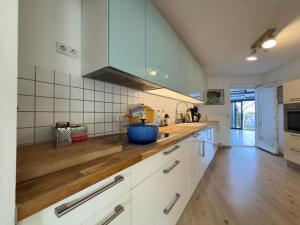 a kitchen with white cabinets and a wooden counter top at Haus zum Ordenswald in Neustadt an der Weinstraße +16 photos