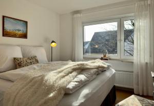 a white bedroom with a bed and a window at Haus zum Ordenswald in Neustadt an der Weinstraße